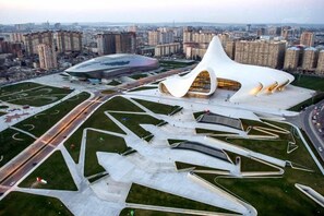 A modern architectural complex with a distinctive white building and a stadium. - Port Rivoli Baku Hotel (Baku)