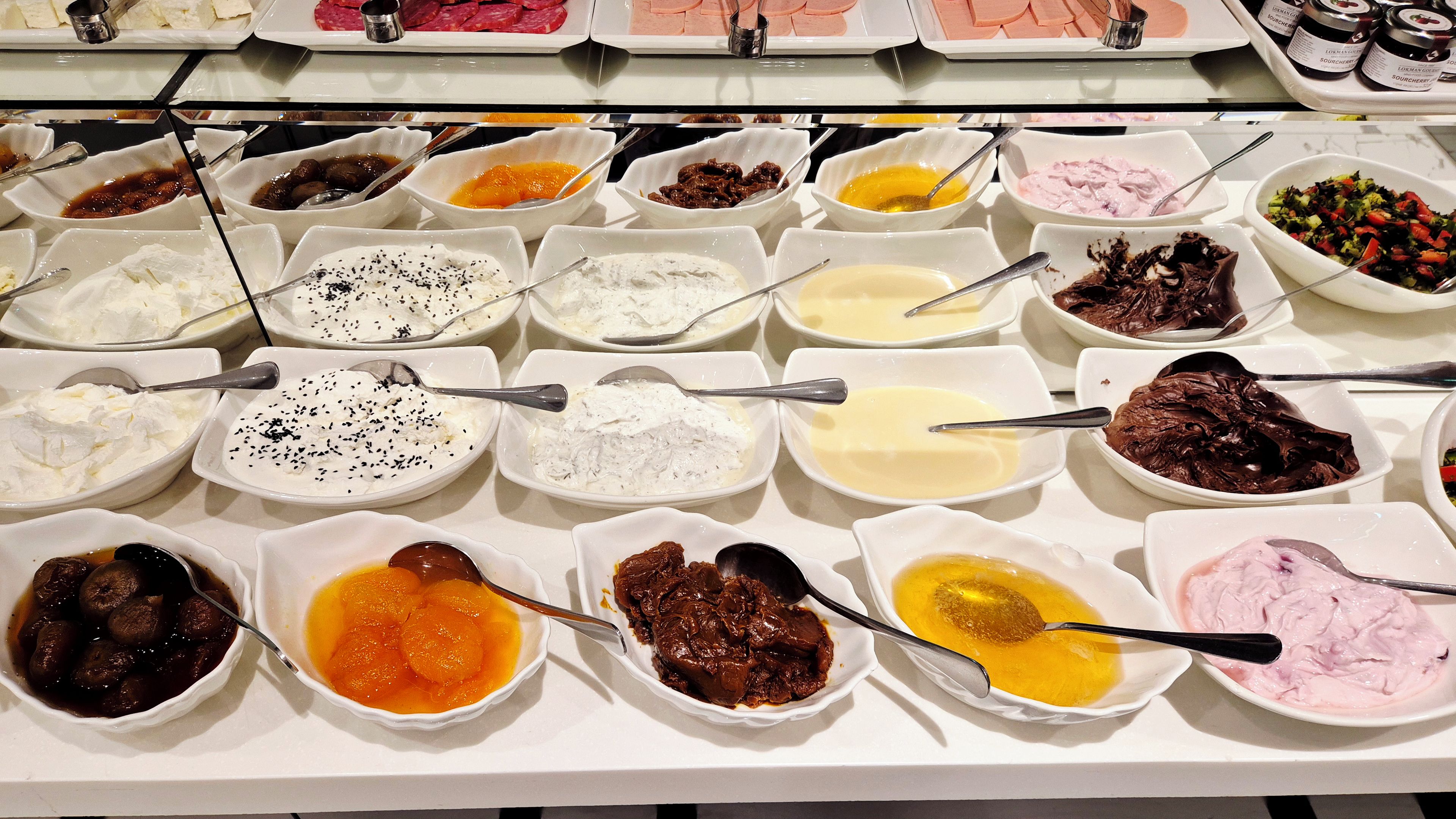 A buffet with various dishes in white bowls, including what appears to be different types of dips and spreads.