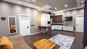A modern kitchen with a brick accent wall, a dining area with a wooden table, and a living room with a sofa.