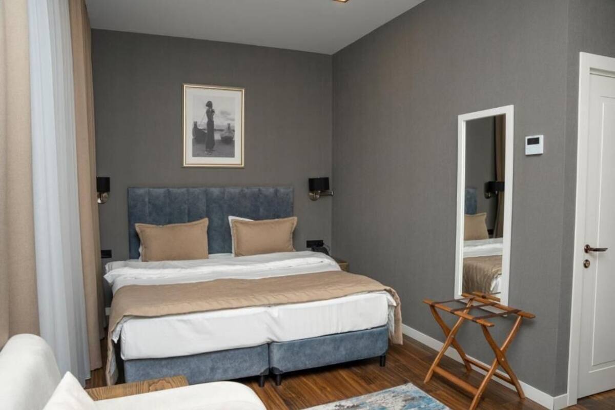 Un dormitorio con cama, mesitas de noche, un espejo y una puerta.