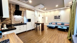 A modern kitchen with white cabinets, a brick accent wall, and a black countertop.