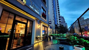 A café with outdoor seating, a modern building facade, and a view of the cityscape. - Port Rivoli Baku Hotel (Baku)
