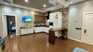 A modern kitchen with a TV, wooden cabinets, and a brick accent wall. - Port Rivoli Baku Hotel (Baku)