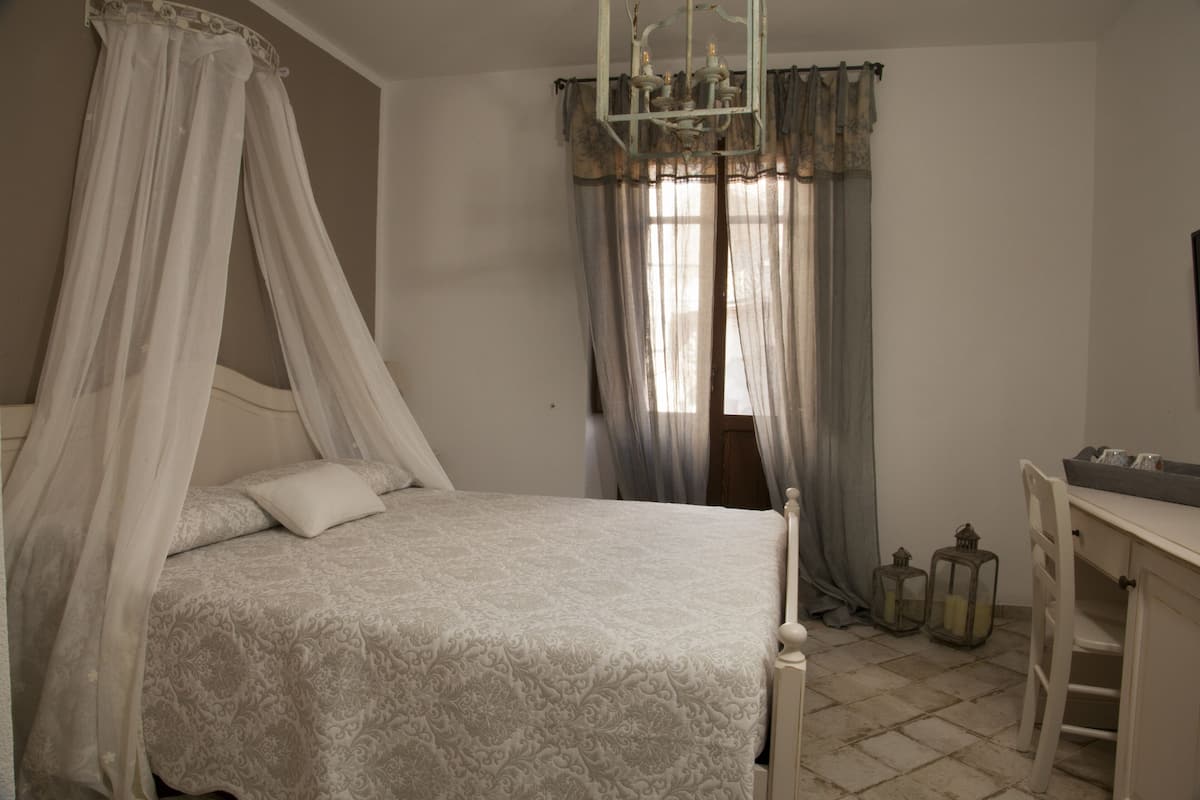 Une chambre à coucher avec un lit à baldaquin, un bureau et deux lanternes.