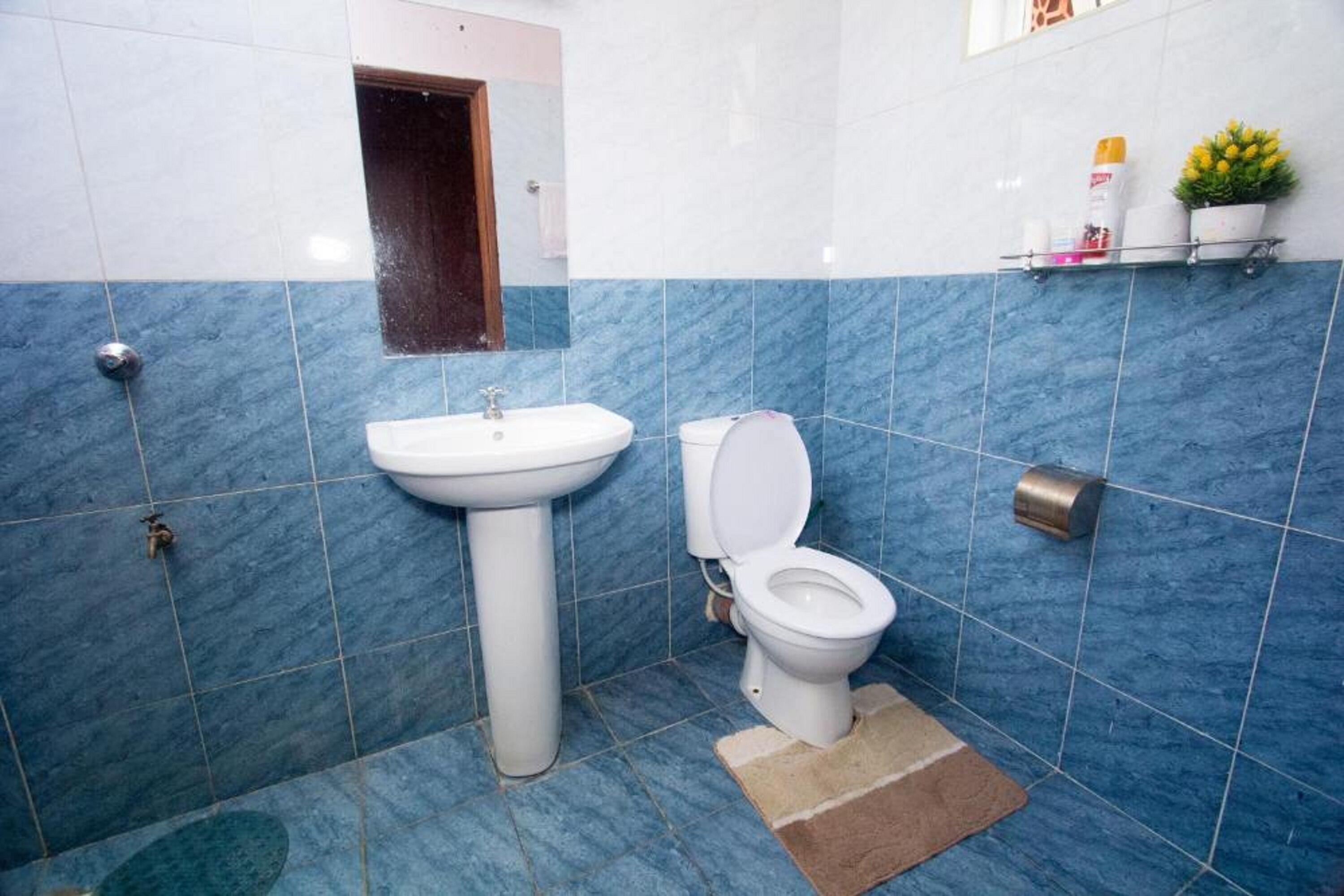 Un baño con lavamanos, inodoro y azulejos azules.