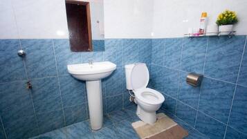 Un baño con lavamanos, inodoro y azulejos azules.