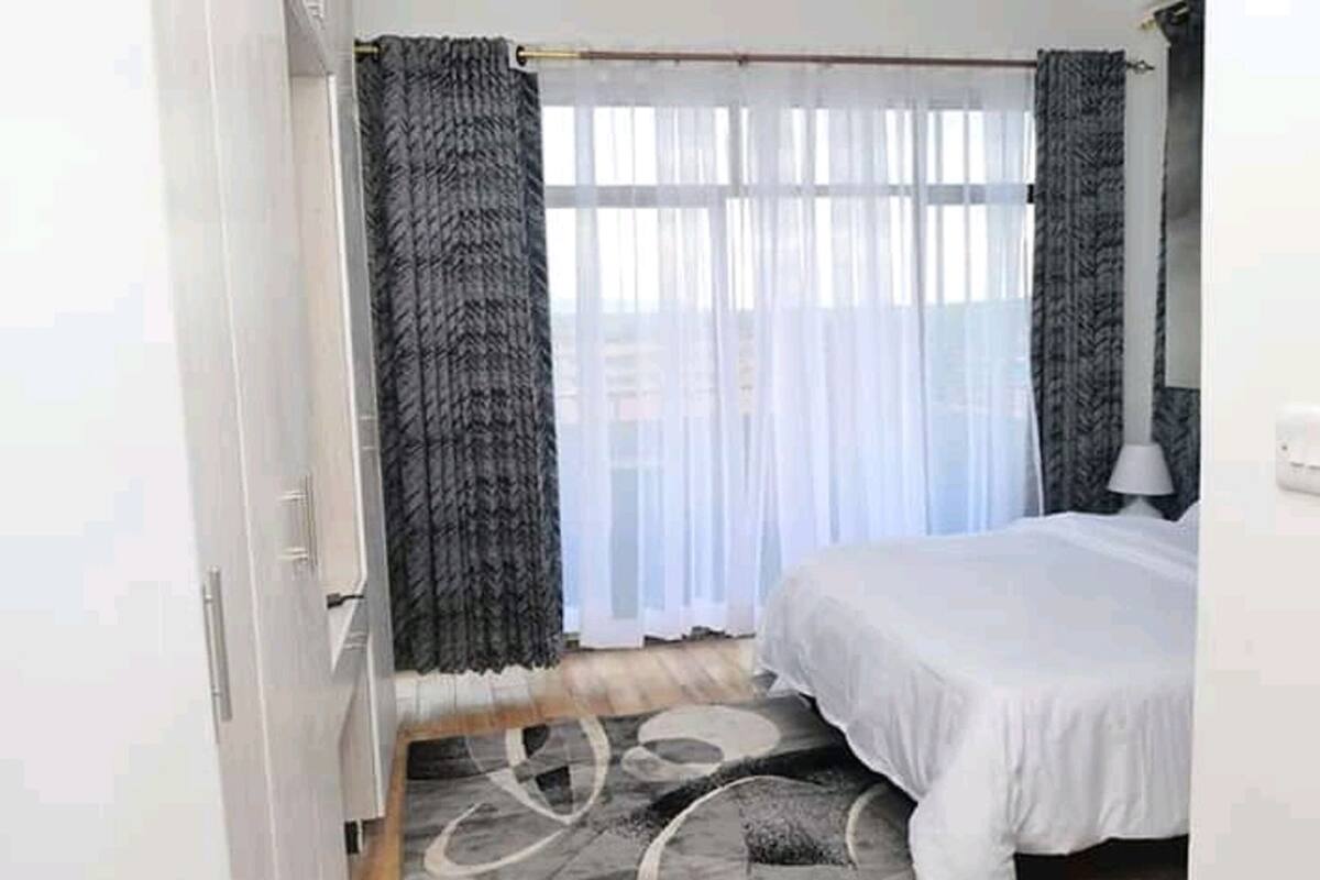Une chambre à coucher avec un lit, des rideaux, une fenêtre et une lampe.