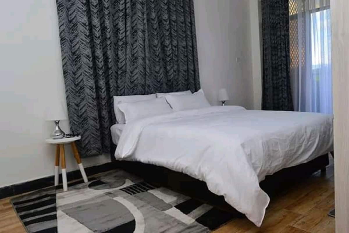 Une chambre à coucher avec un lit, une petite table de chevet, une lampe et un tapis à motifs.