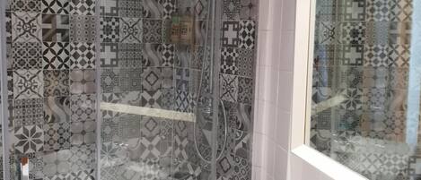 A bathroom with a shower enclosure, a sink with a mirror, and a bottle of blue liquid soap.