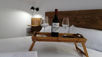 A wooden tray with a bottle of wine and two glasses on a bed.