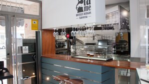 A bar area with stools, a glass display case, and a sign reading "Cuencatame".