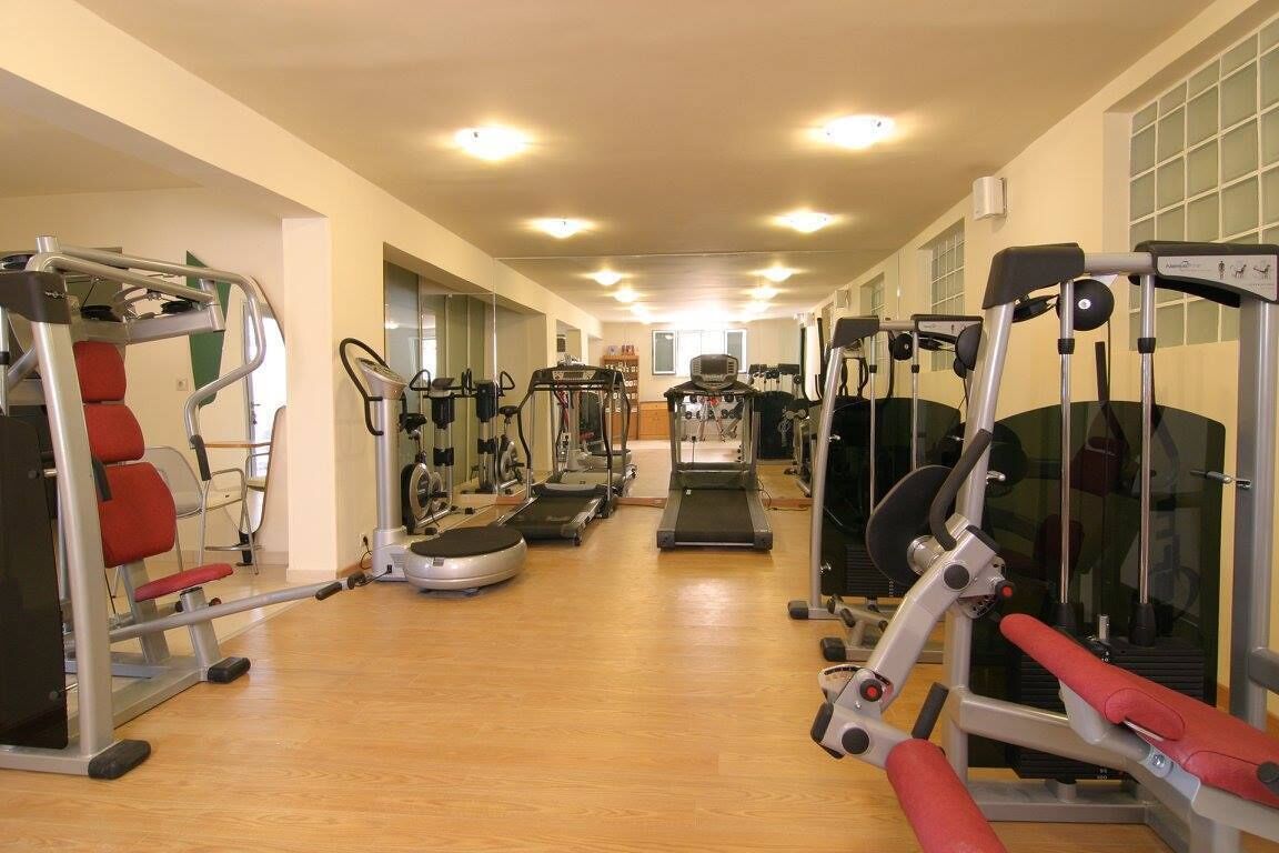 A gym with cardio machines, weight stations, and a mirrored wall.