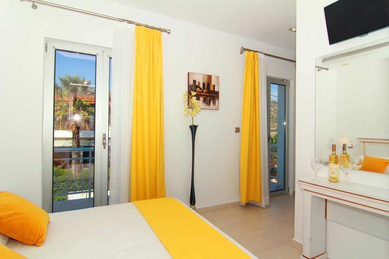 A hotel room with a bed, a desk with a mirror, and a view through a glass door.