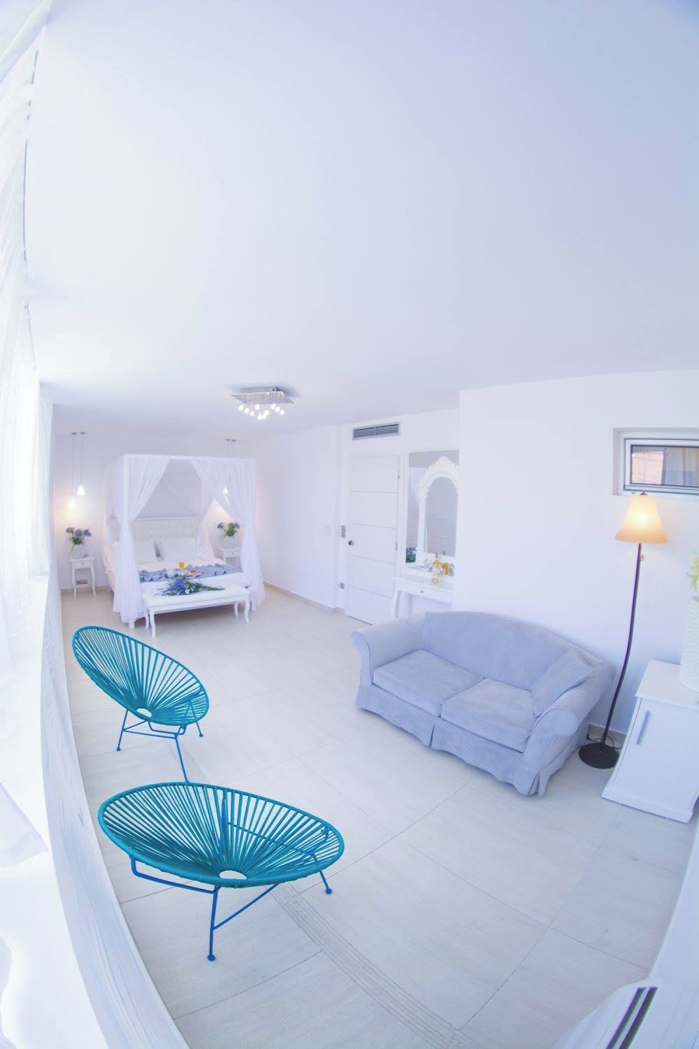 Un interior blanco con una cama, un sofá y dos sillones.