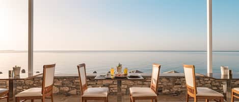 A terrace with a table set for breakfast overlooking the sea.