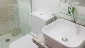 A bathroom with a white toilet, a white sink, and a glass shower enclosure. - Apartment between the airport and the beach. (Boa Viagem)