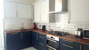 Une cuisine avec des meubles blancs, une cuisinière à gaz, un grille-pain et un four à micro-ondes.