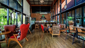A spacious coffee shop with wooden flooring, red and brown chairs, and a bar area. - Onesook Resort Sukhothai (Sukhothai)