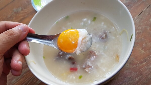 Un tazón de sopa con una cuchara sosteniendo un trozo de carne y un huevo duro.