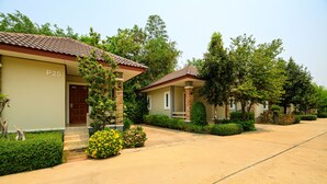A row of two-story houses with a tiled roof, a paved driveway, and well-maintained gardens. - Onesook Resort Sukhothai (Sukhothai)