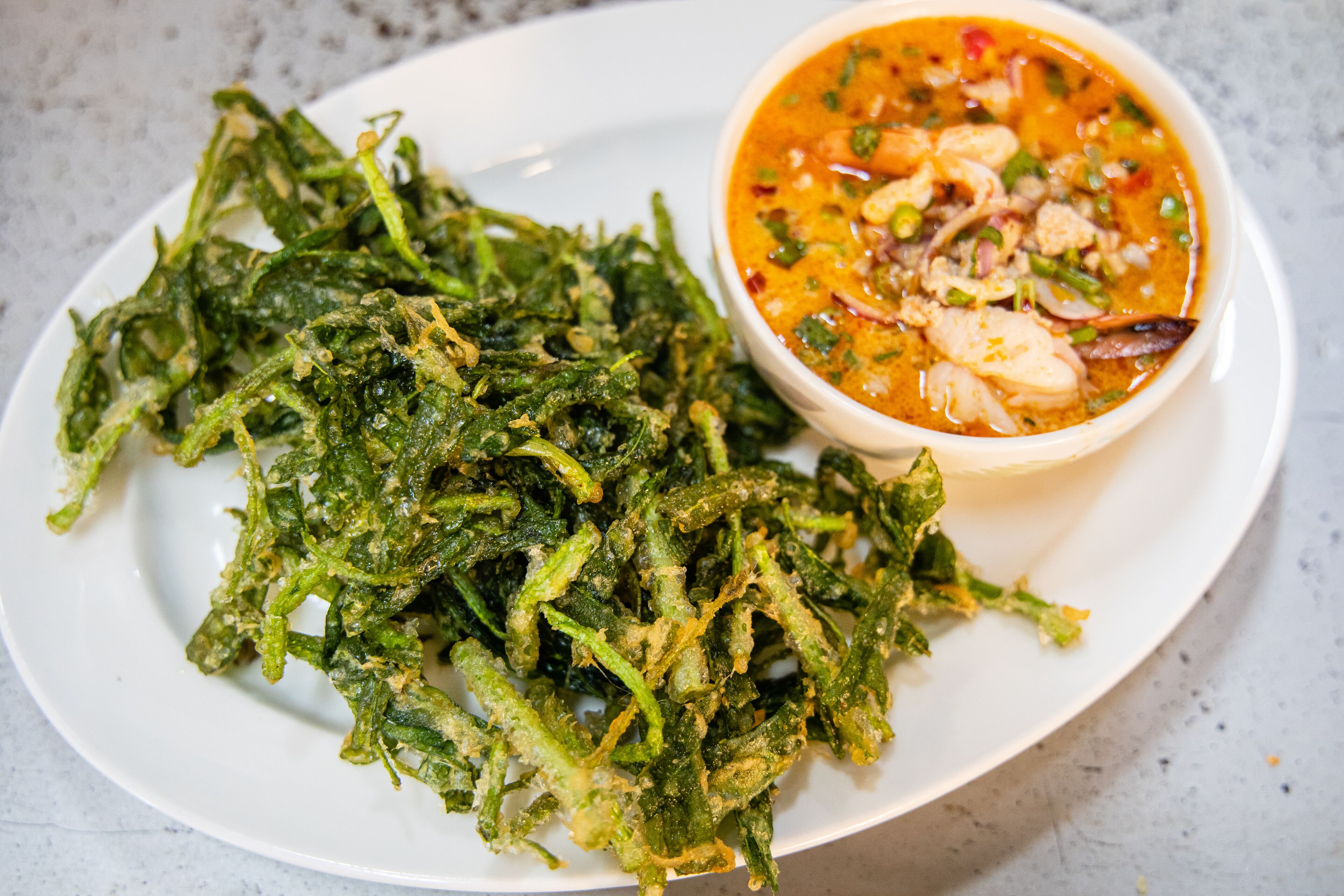 Un plato de verduras verdes fritas y un tazón de sopa.