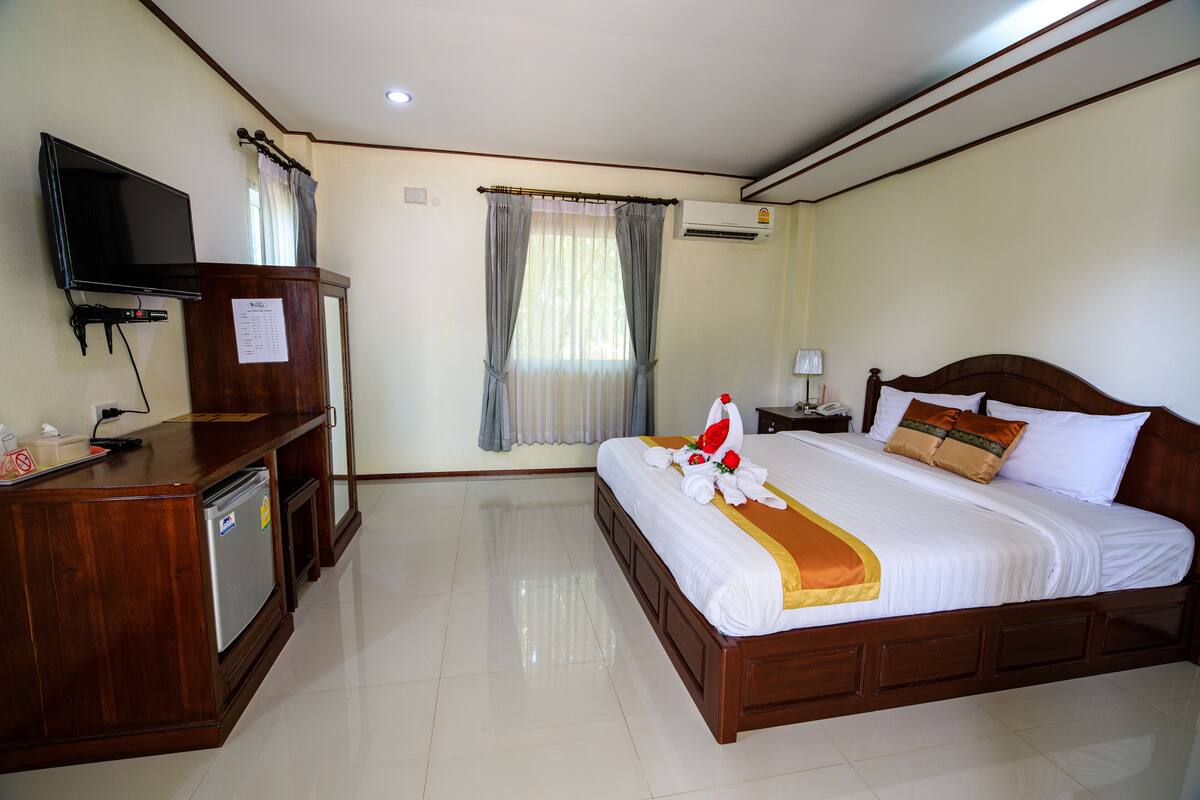 Habitación de hotel con cama, televisión, escritorio y refrigerador.
