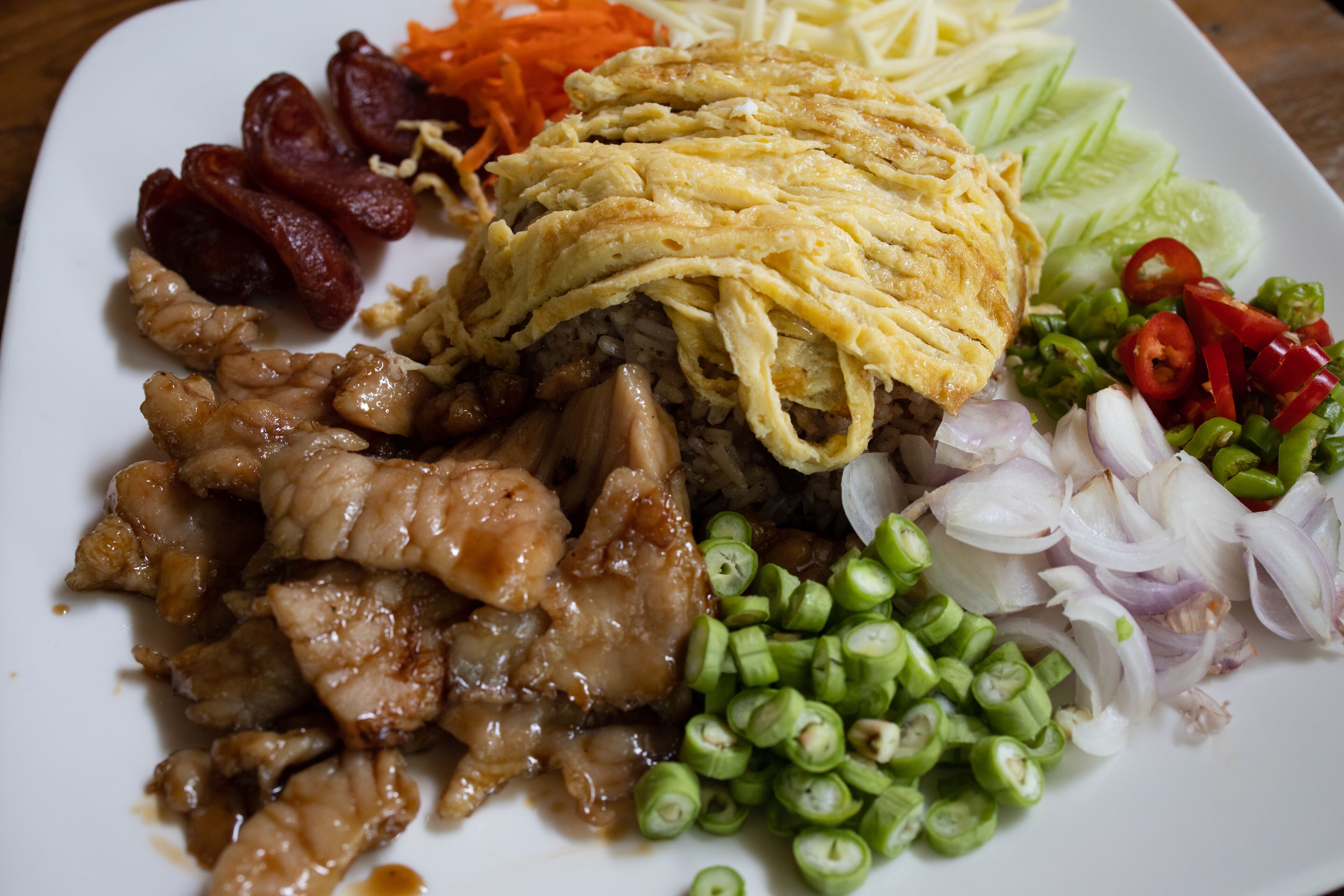 A plate of food with various items including sliced meat, vegetables, and a fried egg.