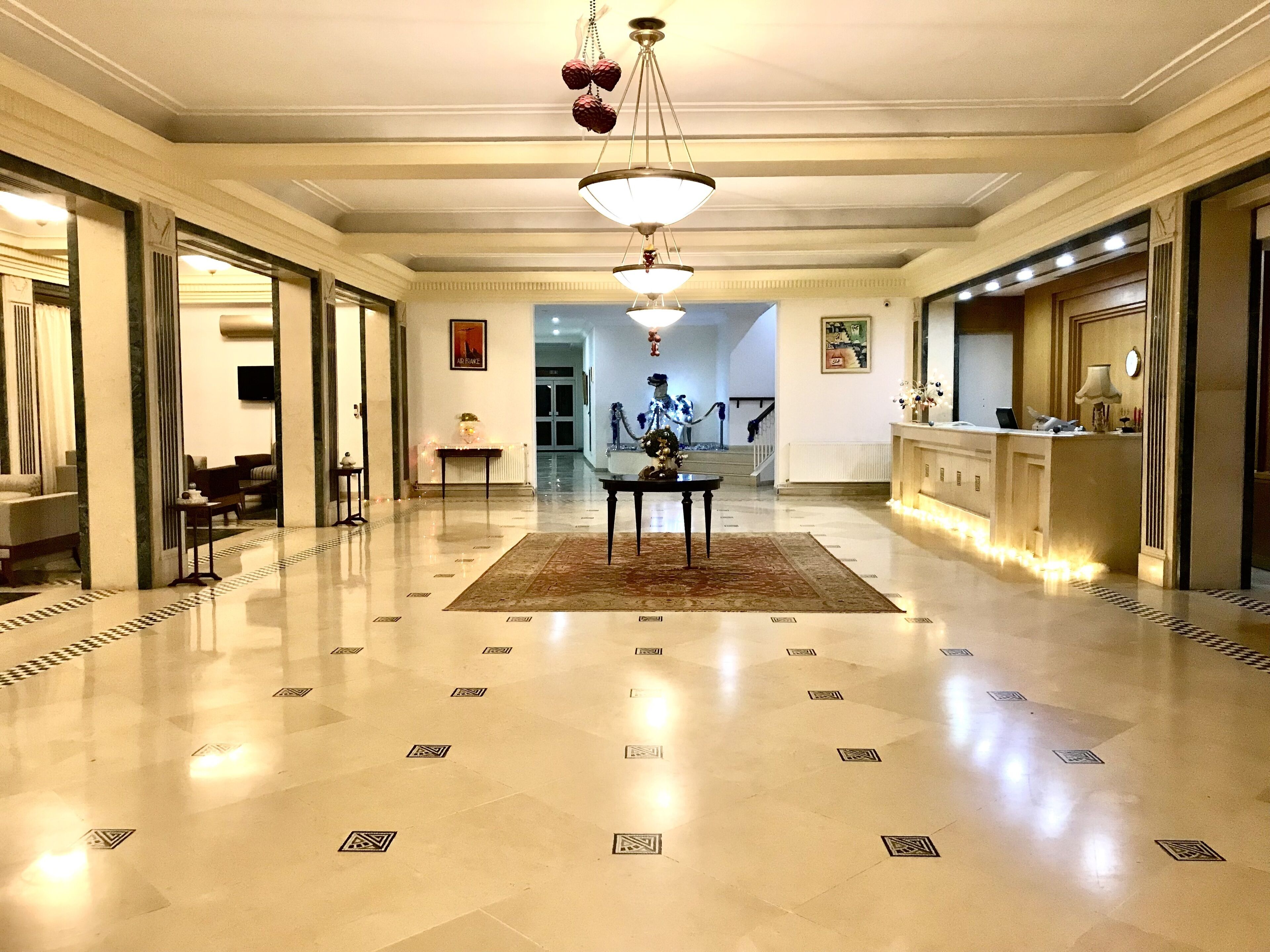 Un hall d’entrée spacieux, doté d’un sol à motifs en damier, d’un comptoir de réception et d’un escalier menant à un autre étage.