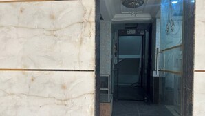 A marble hallway with a glass door leading to a room.