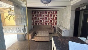 A lobby with a sofa, a small table, a chandelier, and a patterned wall.