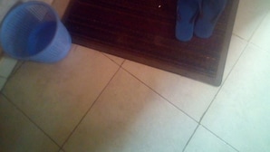 Un estri sol de fusta amb un parell d'esmillots blaus a sobre, un cubet blau i un paviment de rajoles.