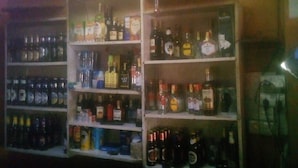 Zona de bar amb prestatges plens de diverses ampolles de licors.