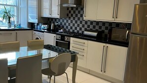 Une cuisine moderne avec des armoires blanches, un réfrigérateur en acier inoxydable et un dosseret à carreaux.