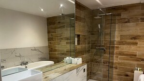 Une salle de bain moderne avec un mur en bois, une douche en verre, une baignoire blanche et des toilettes.