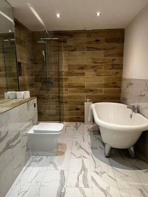 A modern bathroom with a glass-enclosed shower, a freestanding bathtub, and a toilet.