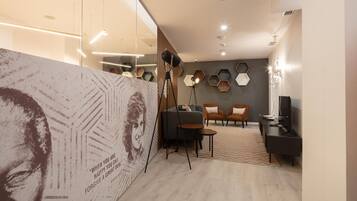 Una sala de estar moderna con un separador de vidrio, un sofá, dos sillones, una mesa de centro y un televisor.