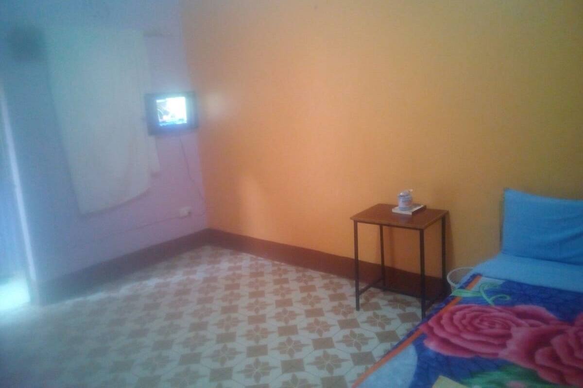 A bedroom with a bed, a small table, and a wall-mounted TV.
