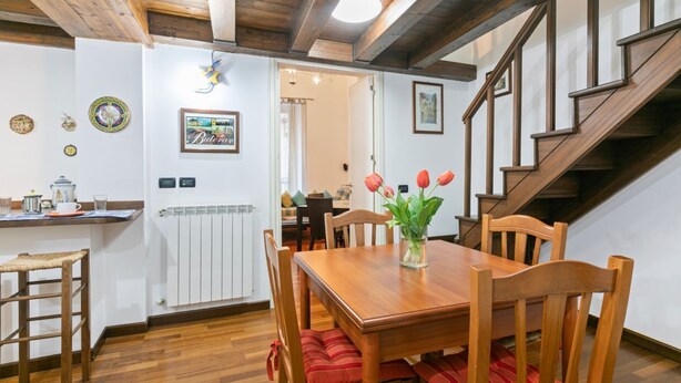 A dining area with a wooden table, chairs, and a vase of flowers.