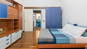 A bedroom with a bed, wooden wardrobe, and a small kitchenette area.