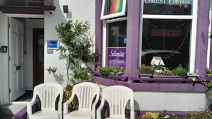 Une devanture de magasin violette avec une enseigne indiquant « Selenite Gifts & Crystals », une enseigne néon indiquant « Postes à pourvoir » et une autre indiquant « Programme d’hébergement pour les visiteurs agréé par Blackpool ».