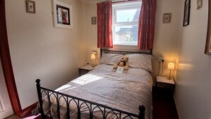 A bedroom with a bed, a teddy bear, two bedside lamps, and a window with curtains. - Starlight Guest House (Blackpool)