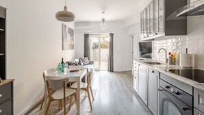 A modern kitchen with a dining area, featuring a central island, pendant lighting, and a view to the outside. - The Best Apartment in Lisbon, Praça da Alegria (Lisboa)