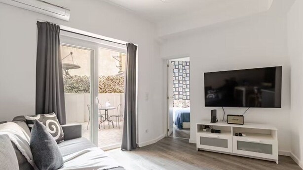 A modern living room with a sofa, TV, and sliding glass doors leading to an outdoor area. - The Best Apartment in Lisbon, Praça da Alegria (Lisboa)