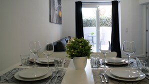 A dining table set with plates, cutlery, and glasses, a potted plant, and a view of a balcony with a sofa and chairs. - The Best Apartment in Lisbon, Praça da Alegria (Lisboa)