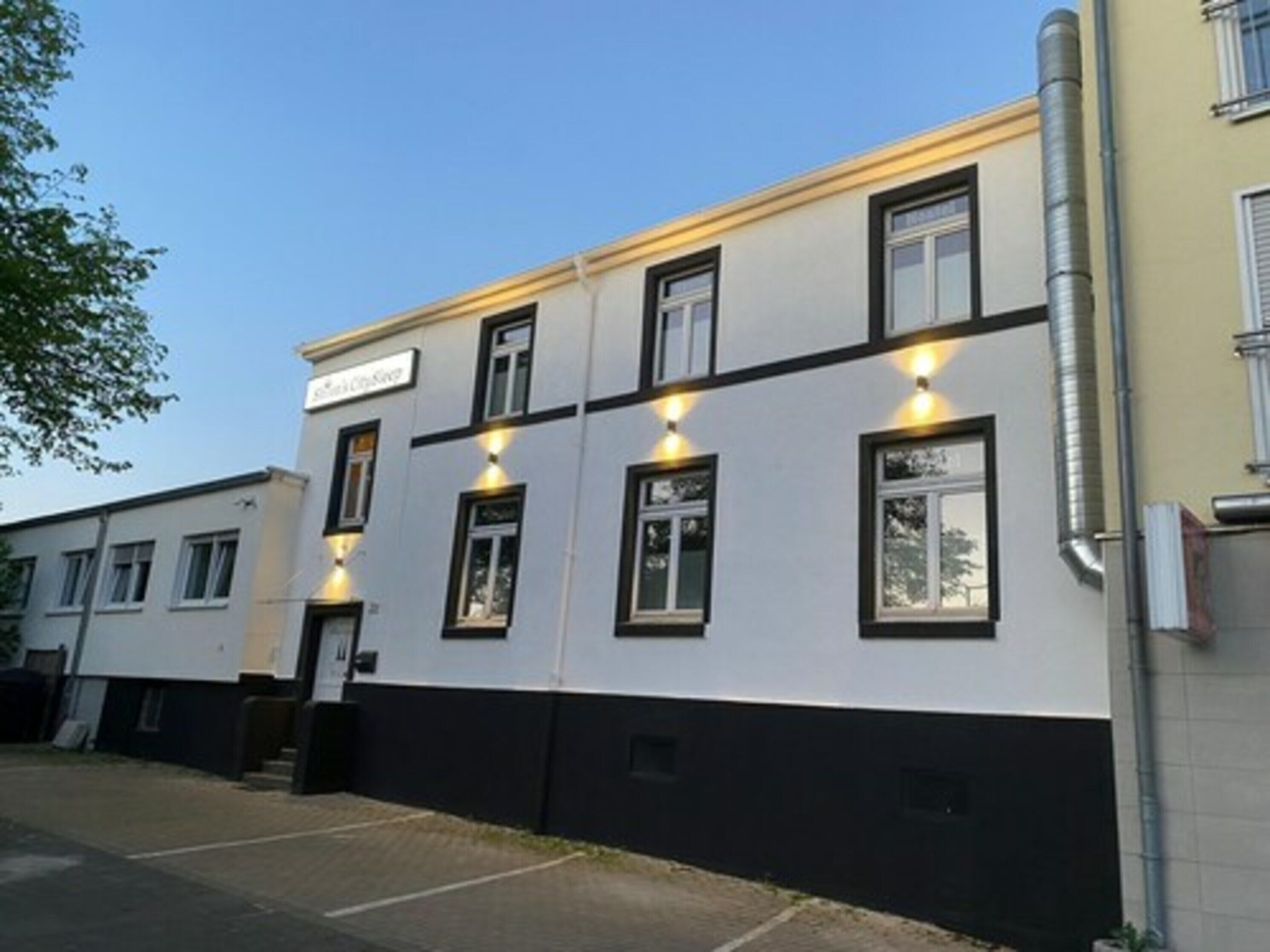 A building with a white facade and black trim, featuring multiple windows and a sign that reads "The Old House."