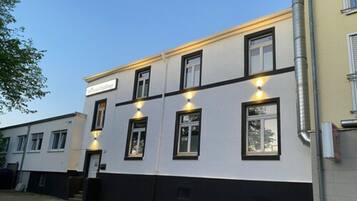 A building with a white facade and black trim, featuring multiple windows and a sign that reads "The Old House."