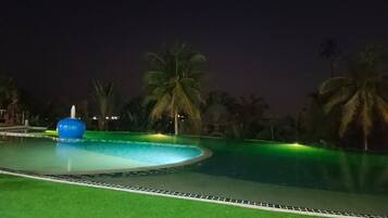 A swimming pool with a blue water feature and palm trees in the background.