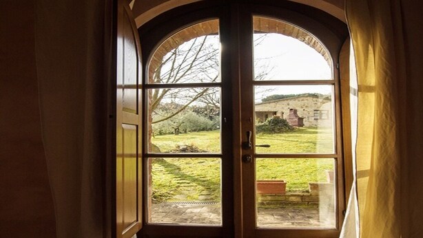 A bay window with a view of a grassy area and a building in the distance. - NOBLE FARM HOLIDAY APARTMENT (Montepulciano Siena)