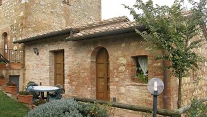 A rustic stone building with a tiled roof, a wooden door, and a small table with chairs outside. - NOBLE FARM HOLIDAY APARTMENT (Montepulciano Siena)