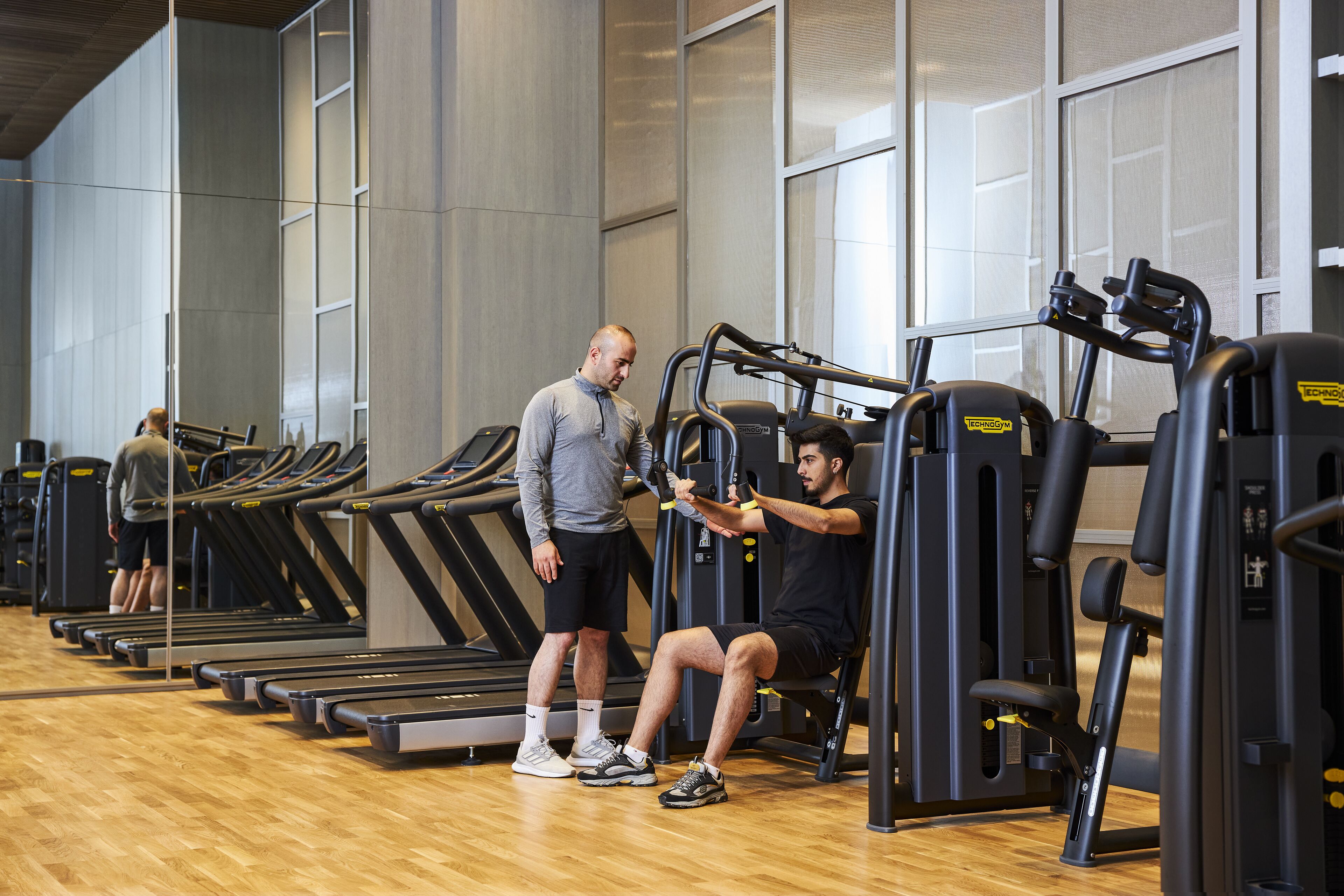 Una palestra con tapis roulant, una macchina per esercizi a sedere e una persona che la utilizza.